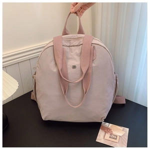 Detail of macaron pink waterproof nylon backpack showing metal logo and wide straps