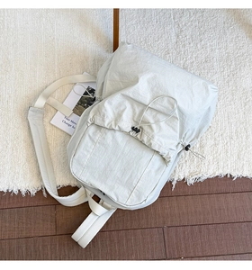 Detail of light grey nylon backpack showing pleated texture and drawstring closure