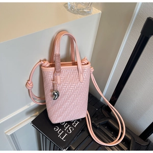 Détail d'un petit sac seau tissé rose avec breloque argentée et bandoulière à nœud