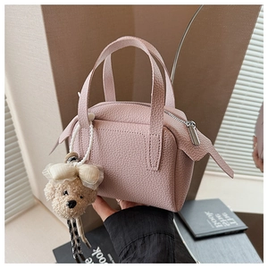 Détail d'un sac à main en cuir rose clair avec un charmant pendentif ours en peluche