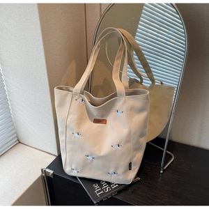 Close-up of beige canvas tote bag with embroidered dachshunds and premium leather logo tag
