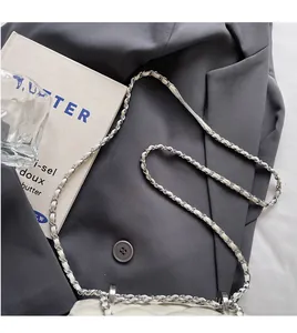 Close-up of white quilted leather chain strap with silver metal detail on a suit background