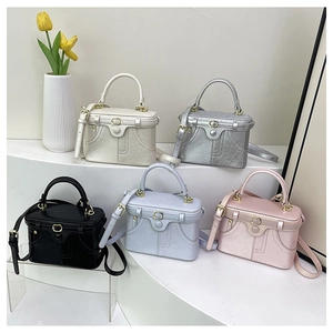Multi-colored box handbags in leather with gold clasps shown on a white display stand