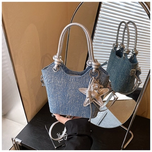 Detail of glittery blue crossbody bucket bag with silver knotted handle and star charm
