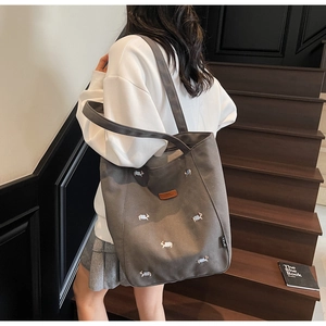 Detail of grey canvas tote bag featuring colorful dog embroidery and leather patch