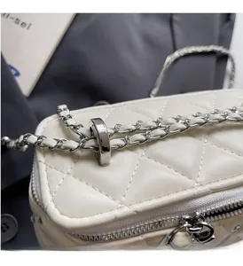 Close-up of beige quilted crossbody bag with silver chain and leather woven strap