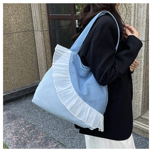 Detail view of light blue denim tote bag with layered white organza ruffle trim on side