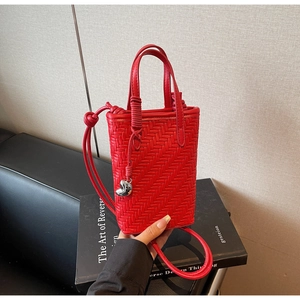 Détail macro du mini sac seau tressé rouge avec un pendentif en métal argenté chic