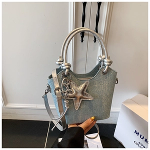 Close-up of denim bucket bag featuring silver rivets and a metallic star charm