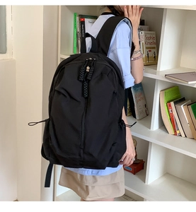 Detail view of black waterproof nylon backpack featuring vertical zip pocket and rope puller