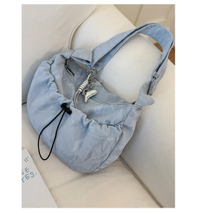 Detail of light blue pleated nylon shoulder bag with unique metallic heart charms