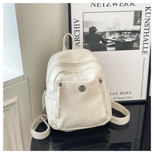 Vue détaillée du sac à dos en nylon crème avec logo GM en métal sur surface réfléchissante