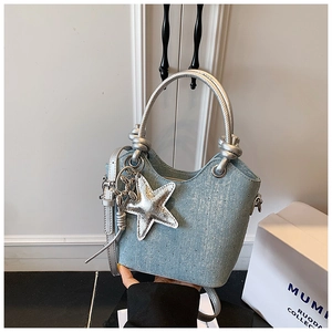 Detail of light blue denim bucket bag featuring rhinestones and star charm accessories