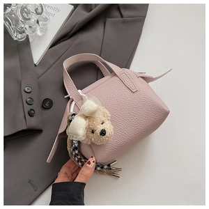 Gros plan d'un mini sac rose grainé avec un porte-clé ours en peluche sur un veston