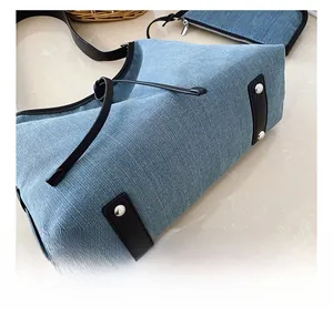 Detail view of denim tote bag base with black leather patches and metal rivets