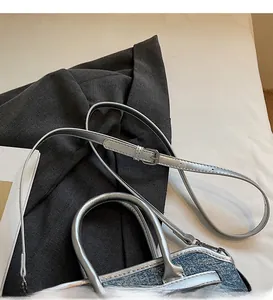 Détails de la bandoulière argentée et de la texture denim sur ce sac à main chic
