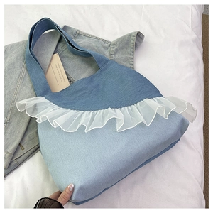 Detail of a patchwork denim tote bag with layered white lace ruffles and soft texture