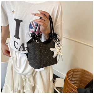 Detail of black polka dot mini bucket bag with ring handle and silver star charm detail