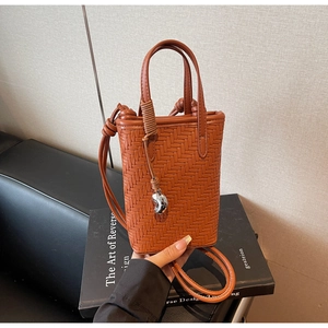 Détail de la texture tressée marron du mini sac seau avec pendentif en métal argenté