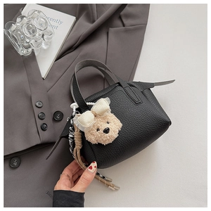 Détail du mini sac à main noir en similicuir avec un charmant pendentif en forme d'ours