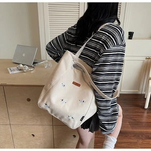 Close-up of off-white canvas tote bag featuring cute dog embroidery and premium leather patch