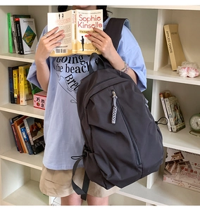 Detail of grey nylon backpack showing multiple zip pockets and side drawstring pouches