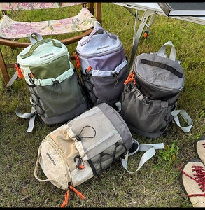 Outdoor backpacks in multiple colors displayed on green grass during a camping trip
