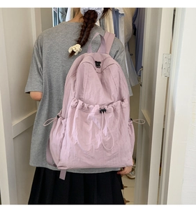 Detail view of light purple nylon backpack with drawstring pockets shown on model back