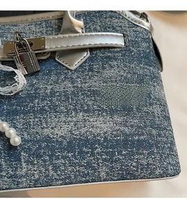 Détail du sac à main en denim bleu avec boucle argentée et élégant charme de perle
