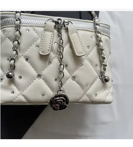 Macro detail of white quilted crossbody bag with sparkling rhinestones and rose pendant