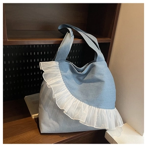 Detailed view of light blue denim tote bag with elegant white lace ruffles on wood shelf