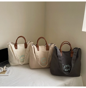 Detail view of canvas tote bags in off-white, khaki and grey with leather handles