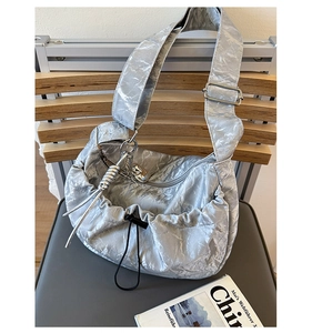 Detail of silver pleated crescent bag with metallic finish and adjustable shoulder strap