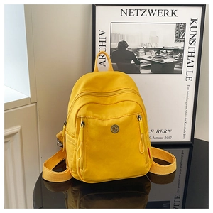 Détail du mini sac à dos en nylon jaune avec multi-poches et logo métallique rond