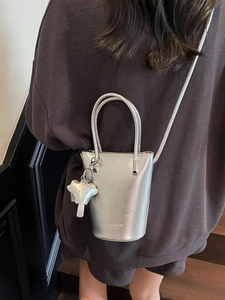 Silver glossy bucket bag with star charm and shoulder strap shown in a lifestyle setting