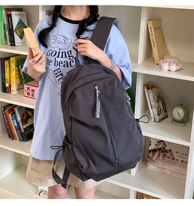 Detail of dark grey backpack featuring a vertical zip pocket and adjustable side straps