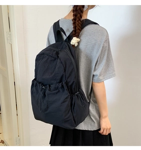 Rear view of a minimalist black nylon outdoor backpack with functional drawstring pockets