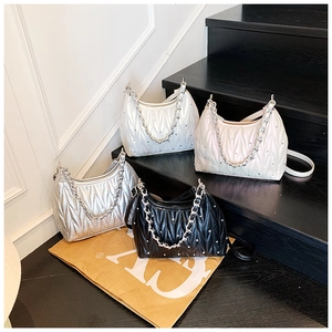 Detailansicht von vier gefalteten Umhängetaschen in Weiß, Beige, Silber und Schwarz