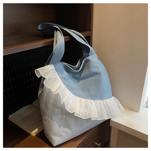 Detailed view of light blue denim tote bag with white lace ruffles in a lifestyle setting