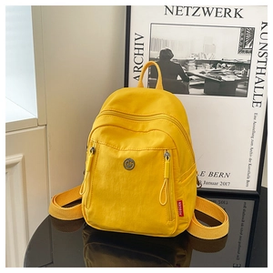 Gros plan d'un mini sac à dos en nylon jaune sur miroir avec détails du logo métallique