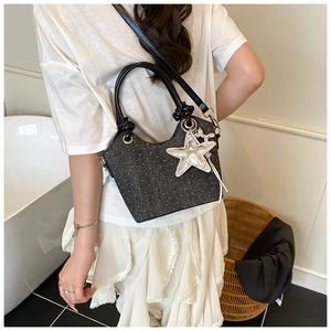 Close-up of a grey bucket bag featuring white dots and a silver star pendant accessory