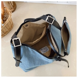 Detail of light blue denim tote bag with adjustable black leather straps and silver buckles