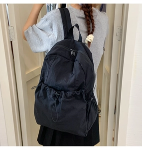 Detailed back view of casual black nylon backpack featuring multiple drawstring pockets