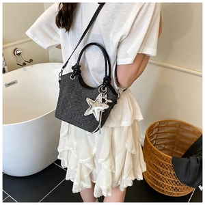 Polka dot denim bucket bag with silver star charm and tassels worn as a crossbody bag
