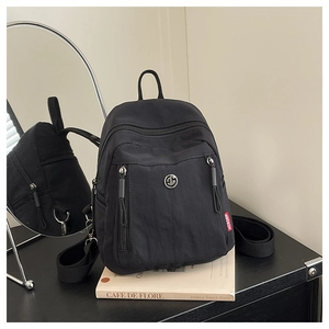 Gros plan du sac à dos en nylon noir avec doubles zips et détails du logo stylé