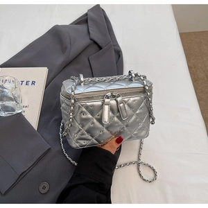 Detail of silver quilted mini bucket bag with crystal accents and chain strap on blazer
