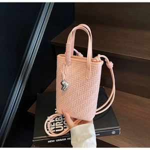 Détail d'un mini sac seau rose en cuir tressé avec pendentif coeur et bandoulière élégante