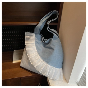 Macro detail of a light blue denim tote bag with white organza ruffles on a shelf