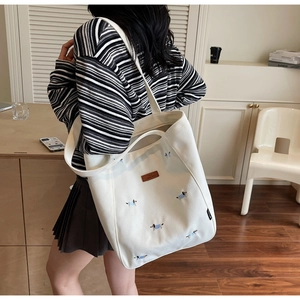 Lifestyle shot of large white canvas tote bag with cute puppy embroidery worn by a model