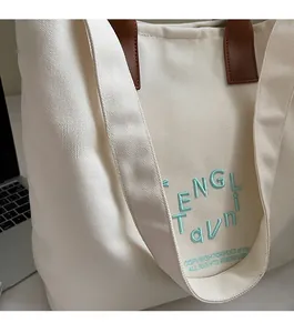 Detail of canvas tote bag with 3D embroidery and durable synthetic leather straps